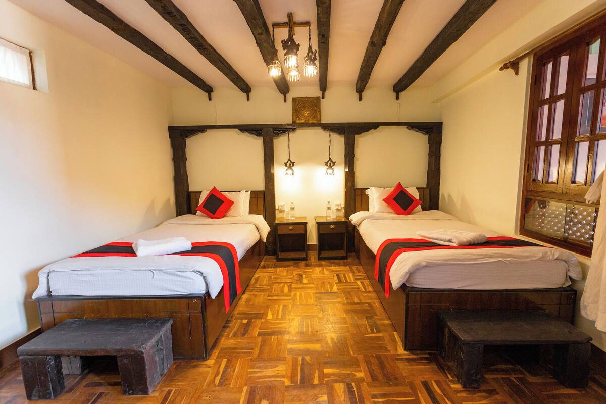Una habitación con dos camas, piso de madera y un candelabro.