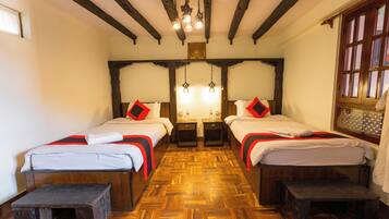 A room with two beds, wooden floors, and a chandelier.