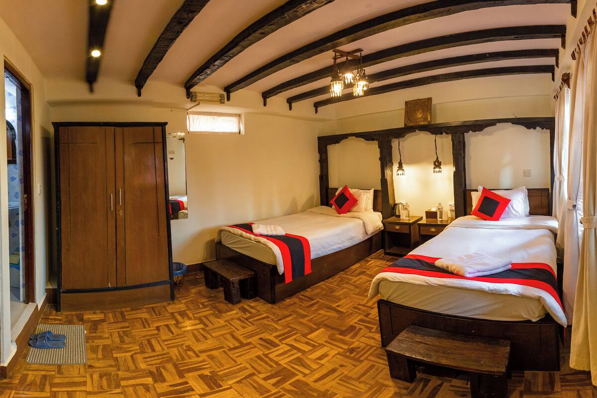 Una habitación con dos camas, piso de madera y un armario de madera.