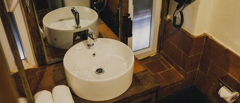 A bathroom with two sinks, a mirror, a towel rack, a toilet, and a shower.