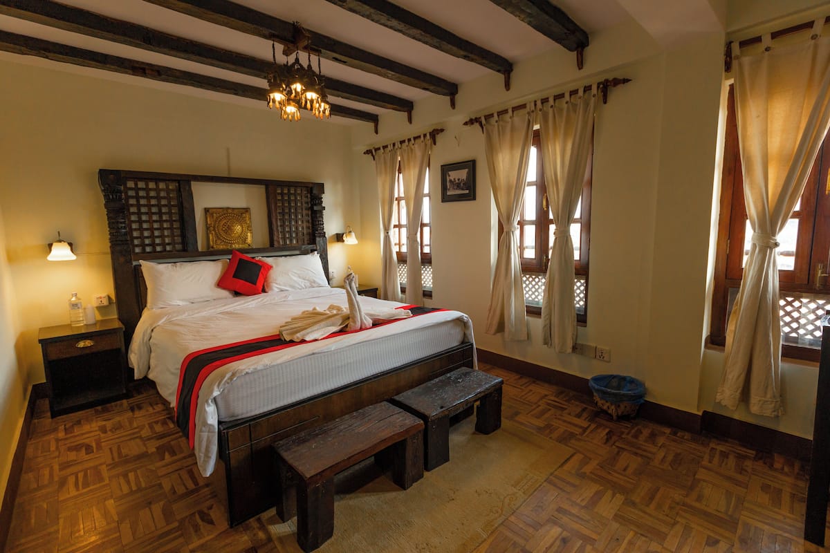 Un dormitorio tradicional con cama de madera, banco y candelabro.