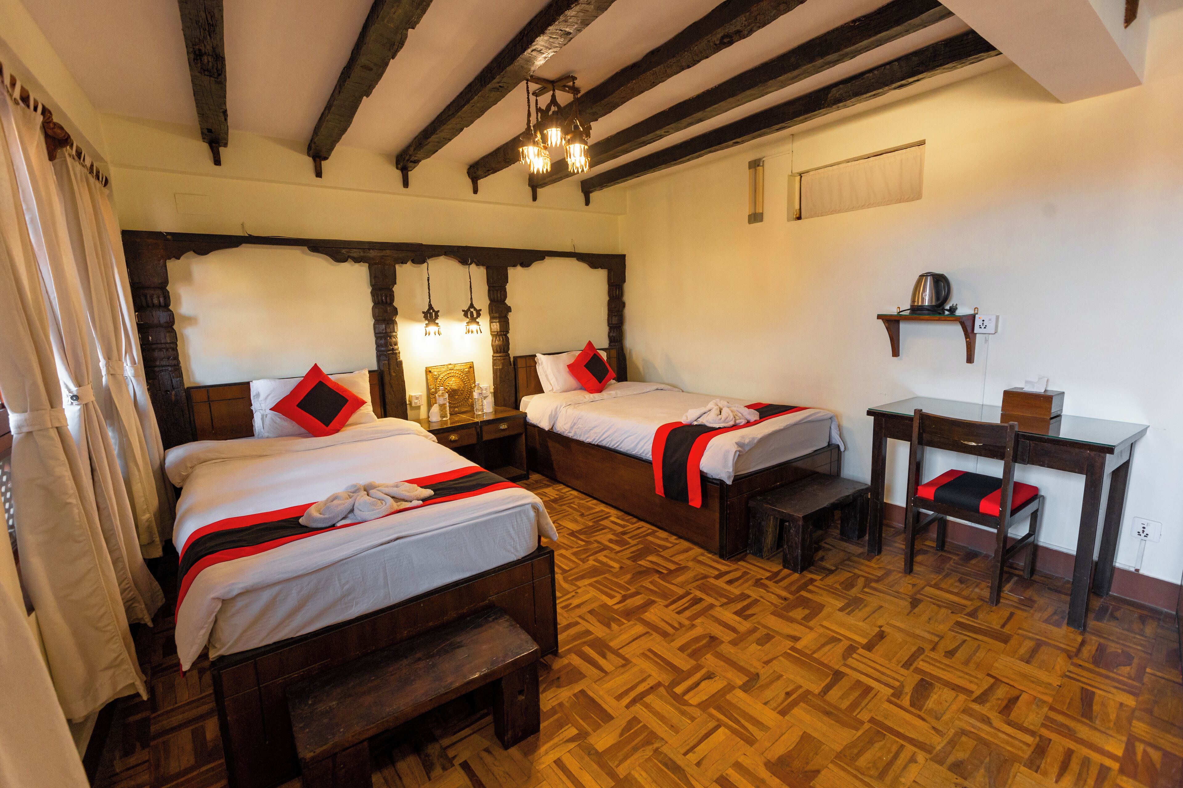 A room with two wooden beds, a wooden desk, and a chair.