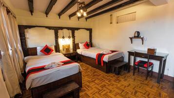 A room with two wooden beds, a wooden desk, and a chair.