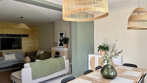 Una sala de estar moderna con un sofá, una mesa de comedor y lámparas colgantes de mimbre.