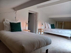 Two single beds with white mattresses and green accent pillows, set against a clean white backdrop.