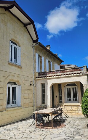Stunning two-story building with a stone facade, red-tiled roof, and charming balcony.
