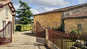 Un sendero adoquinado que conduce a una entrada con puertas de hierro forjado.