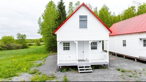 Ett vitt hus med ett rött tak, en veranda och en liten trädgård framför huset.