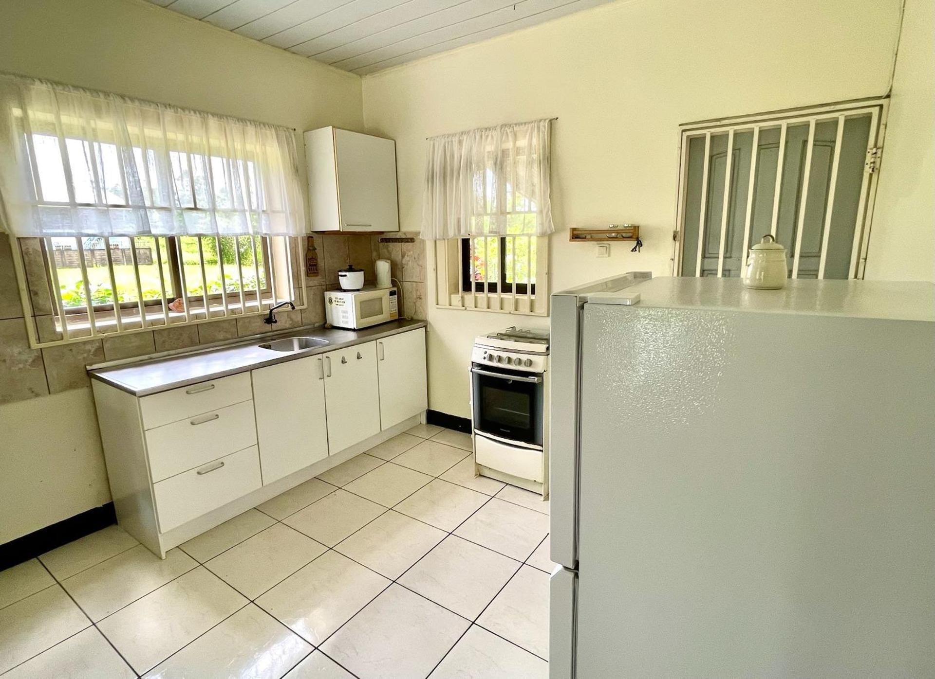A kitchen with white cabinets, a stove, a sink, and a refrigerator.