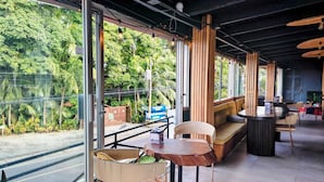 An indoor seating area with a view of lush greenery outside. - Alma Vida Hotel (Quepos)