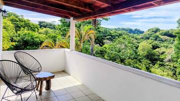 A balcony with two chairs and a small table, overlooking a lush green landscape.