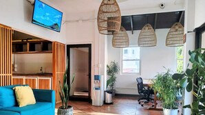 A modern interior with a blue sofa, a coffee table, a Buddha head sculpture, and hanging wicker lamps. - Alma Vida Hotel (Quepos)