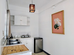 A compact kitchen with a sink, stove, and a small refrigerator. - Alma Vida Hotel (Quepos)