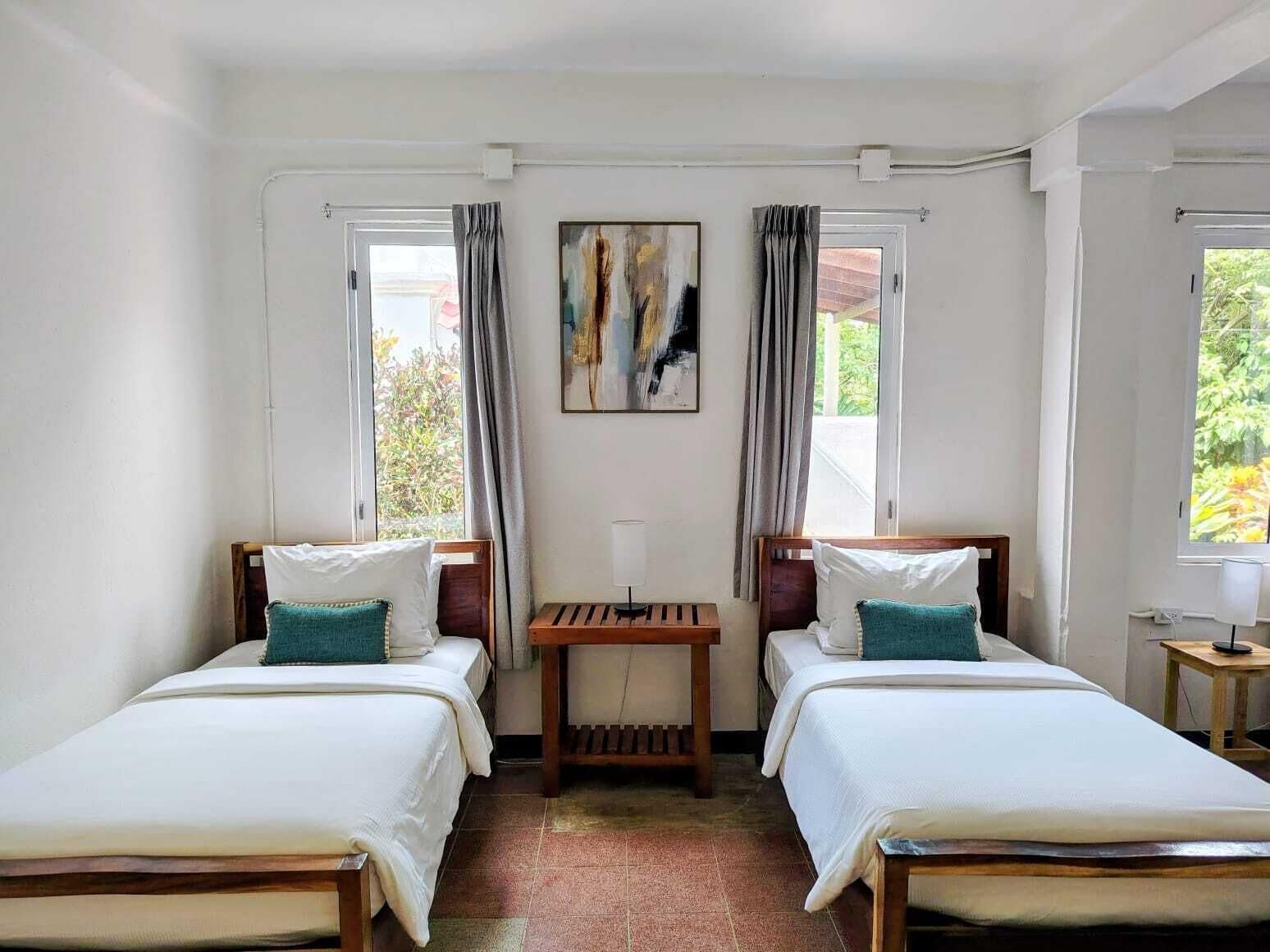 Ein Zimmer mit zwei Betten, einem Tisch und einem Bild an der Wand.