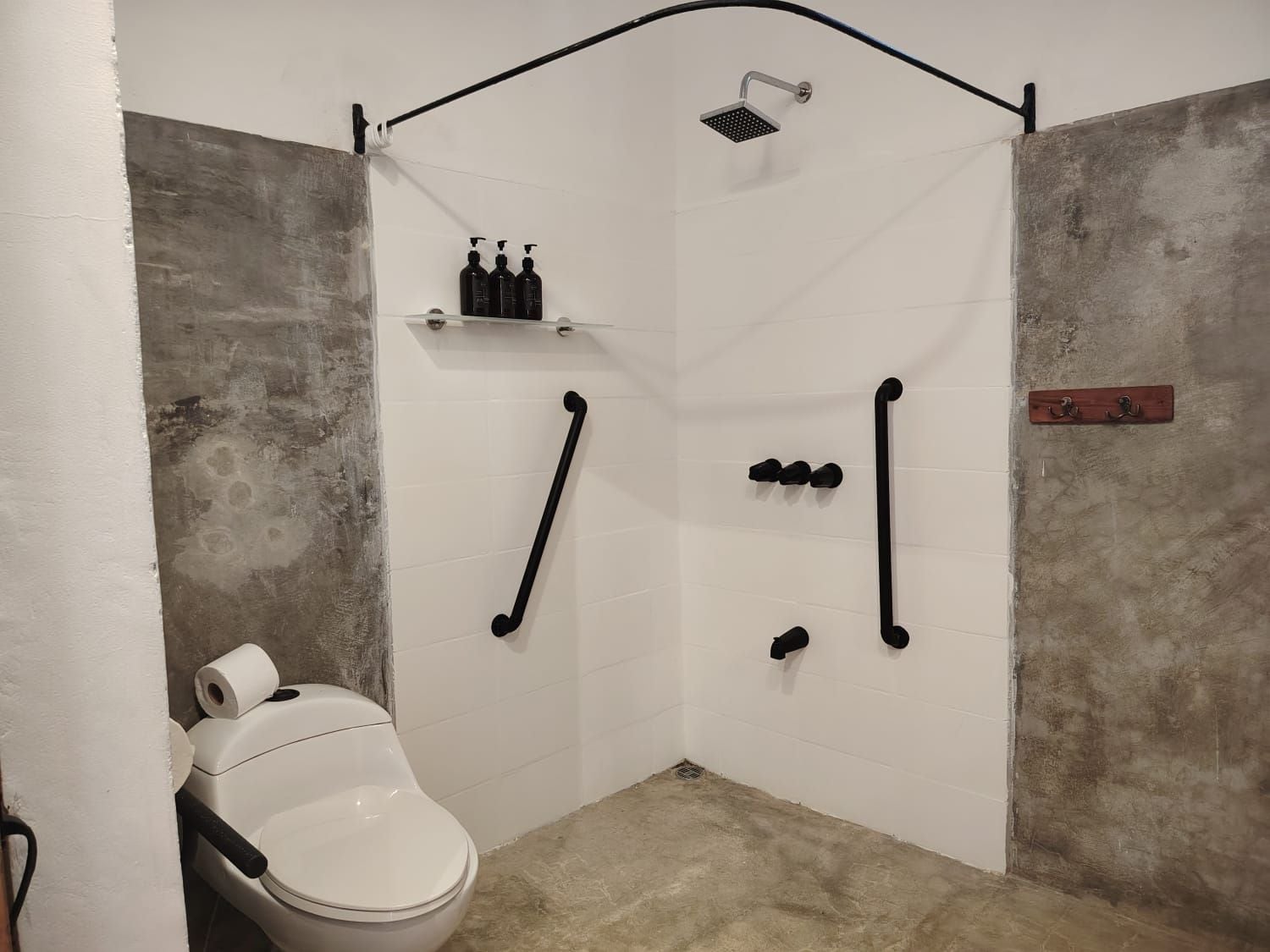 A small, enclosed bathroom with a toilet, shower, and towel rack.