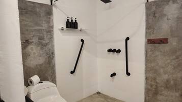 A small, enclosed bathroom with a toilet, shower, and towel rack.