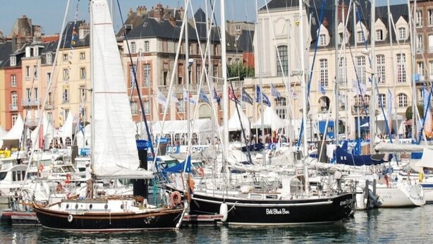 A marina with several sailboats docked, surrounded by historic buildings.