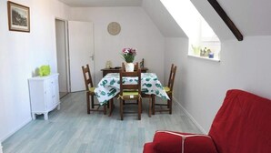 A dining area with a table set for four, a red chair, a white cabinet, and a window with a view.