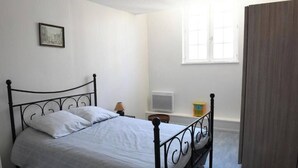 A bedroom with a bed, a radiator, a window, and a picture on the wall.
