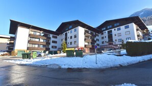 A multi-story building with balconies, a parking area, and snow on the ground. - Domizil Alpine Retreat 11 with balcony (Kaprun)
