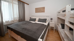 A bedroom with a bed, bedside tables, a radiator, a window with curtains, and a wall with a sign. - Domizil Alpine Retreat 11 with balcony (Kaprun)