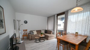 A modern living room with a sofa, a dining table, and a TV. - Domizil Alpine Retreat 11 with balcony (Kaprun)