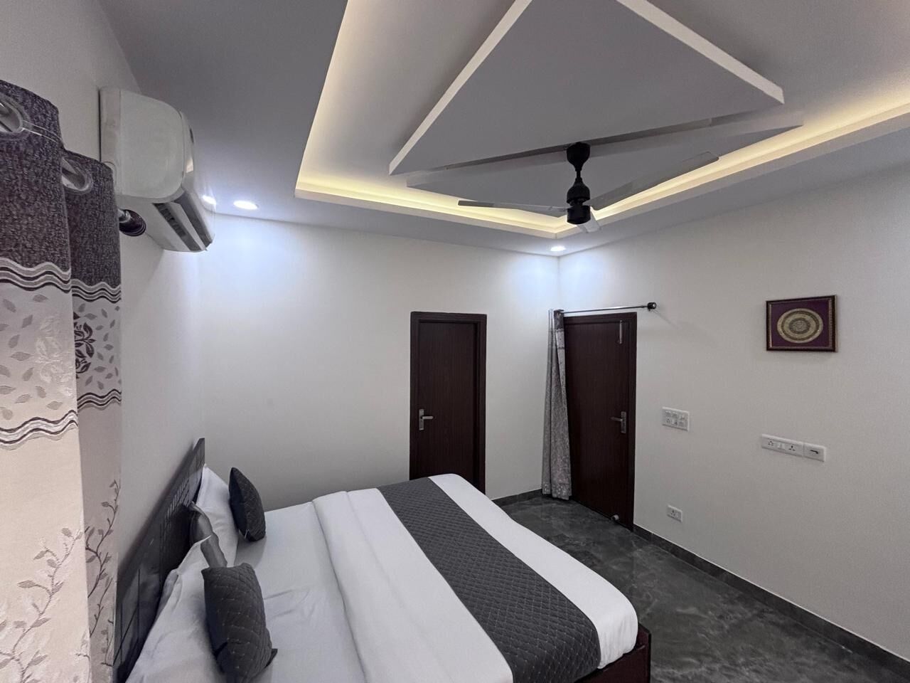 Una habitación de hotel moderna con una cama bien hecha, un ventilador de techo y un equipo de aire acondicionado.