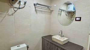 Un baño con inodoro, lavamanos, tocador, espejo, toallero y purificador de aire instalado en el techo.