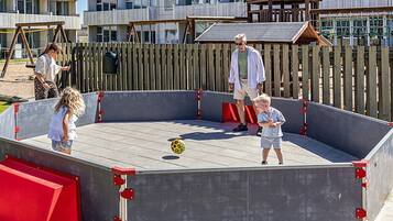 A playground with a large, enclosed play area featuring a red ramp and a soccer ball.