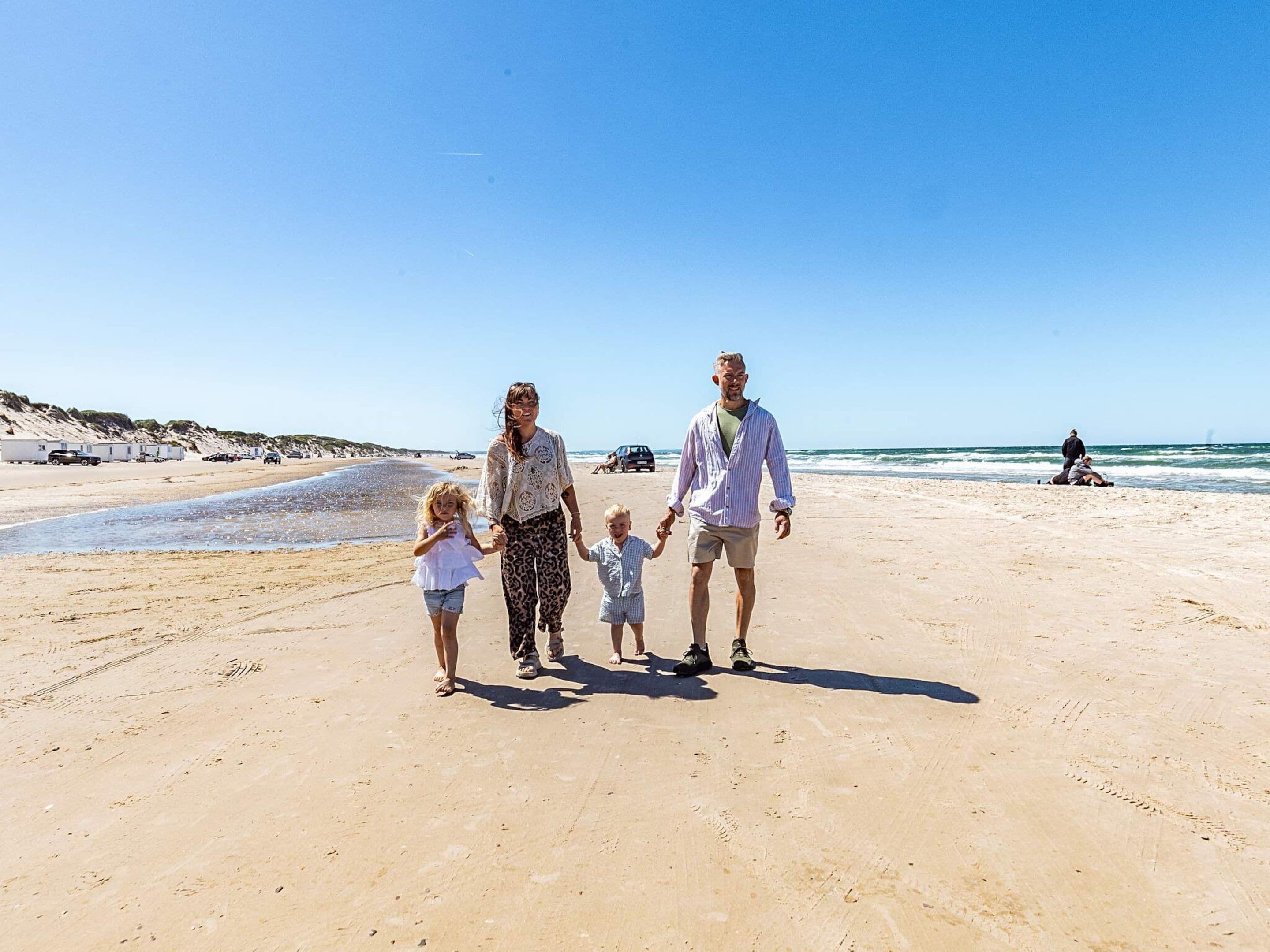 A family walking on a sandy beach with a clear sky.