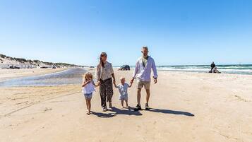 A family walking on a sandy beach with a clear sky.