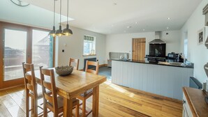 A modern kitchen with a central island, wooden dining table, and chairs. - 2 bedroom accommodation in Chwilog, near Pwllheli (Chwilog, near Pwllheli)