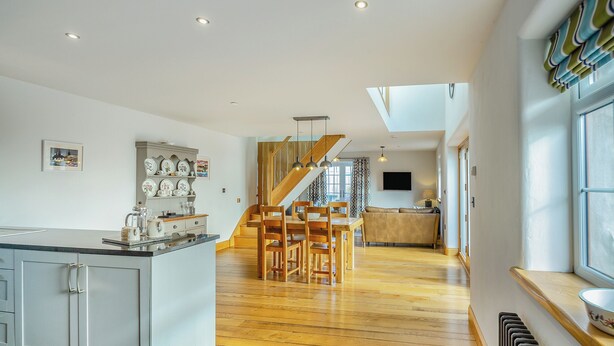 A modern kitchen with a central island, wooden flooring, and a staircase leading to an upper level. - 2 bedroom accommodation in Chwilog, near Pwllheli (Chwilog, near Pwllheli)