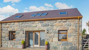 A stone building with a sloped roof, skylights, and large windows. - 2 bedroom accommodation in Chwilog, near Pwllheli (Chwilog, near Pwllheli)