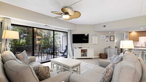 Ein Wohnzimmer mit Sofa, Couchtisch, Fernseher und Deckenventilator.
