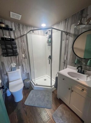 A bathroom with a glass-enclosed shower, a white sink, and a mirror. - Hot Tub Cabin Hideaway Near Tomahawk (Irma)
