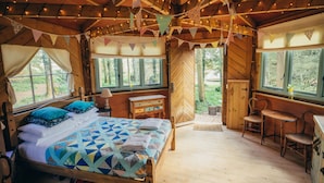 A wooden cabin with a bed, a table, and chairs, and a view of the outdoors. - West Lexham Wellness and Retreat Centre (King's Lynn)