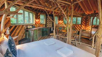 A rustic cabin with a loft bedroom, a dining area, and a kitchen.