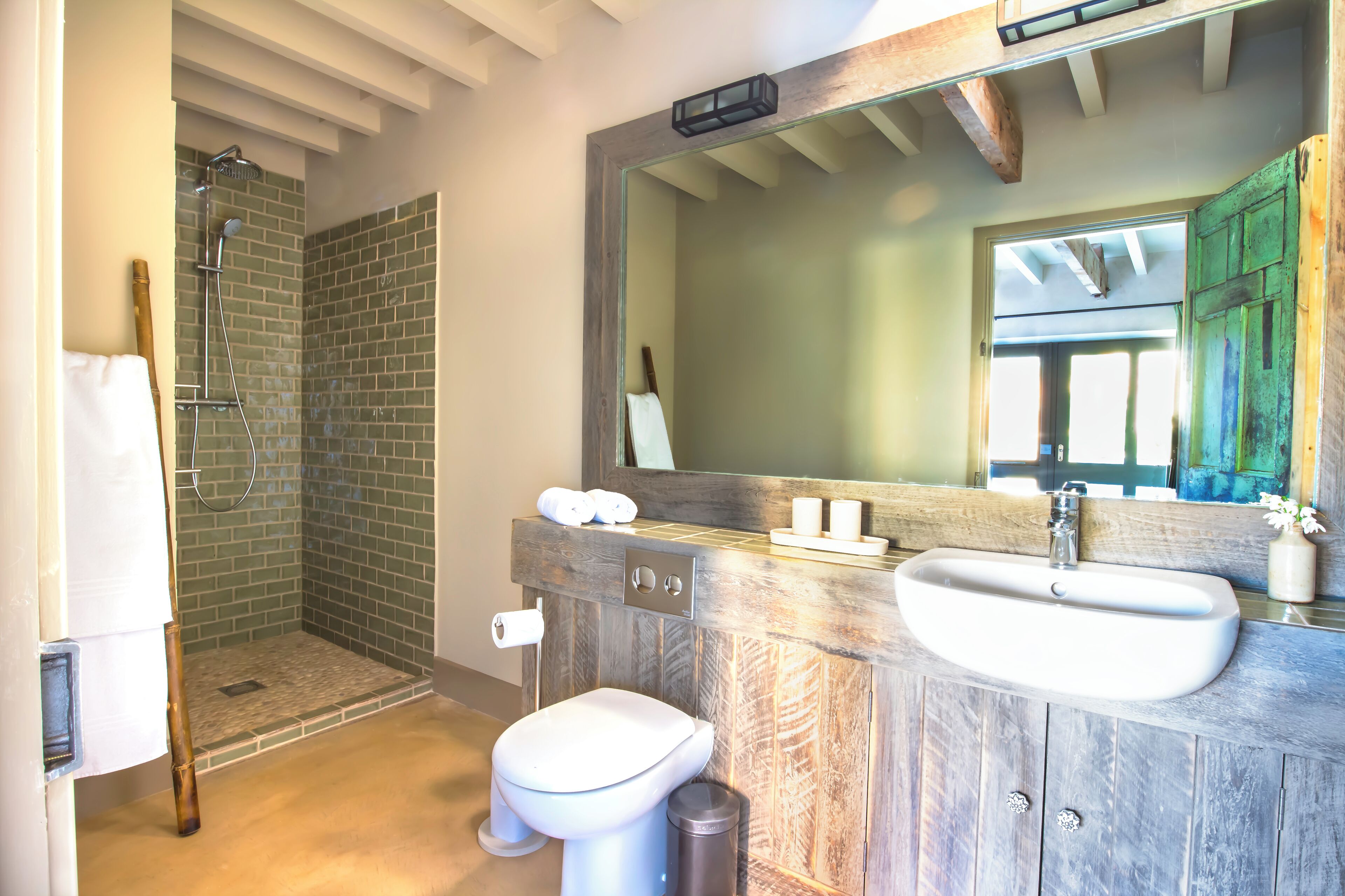 Une salle de bain avec une douche, deux lavabos, des toilettes et un grand miroir.