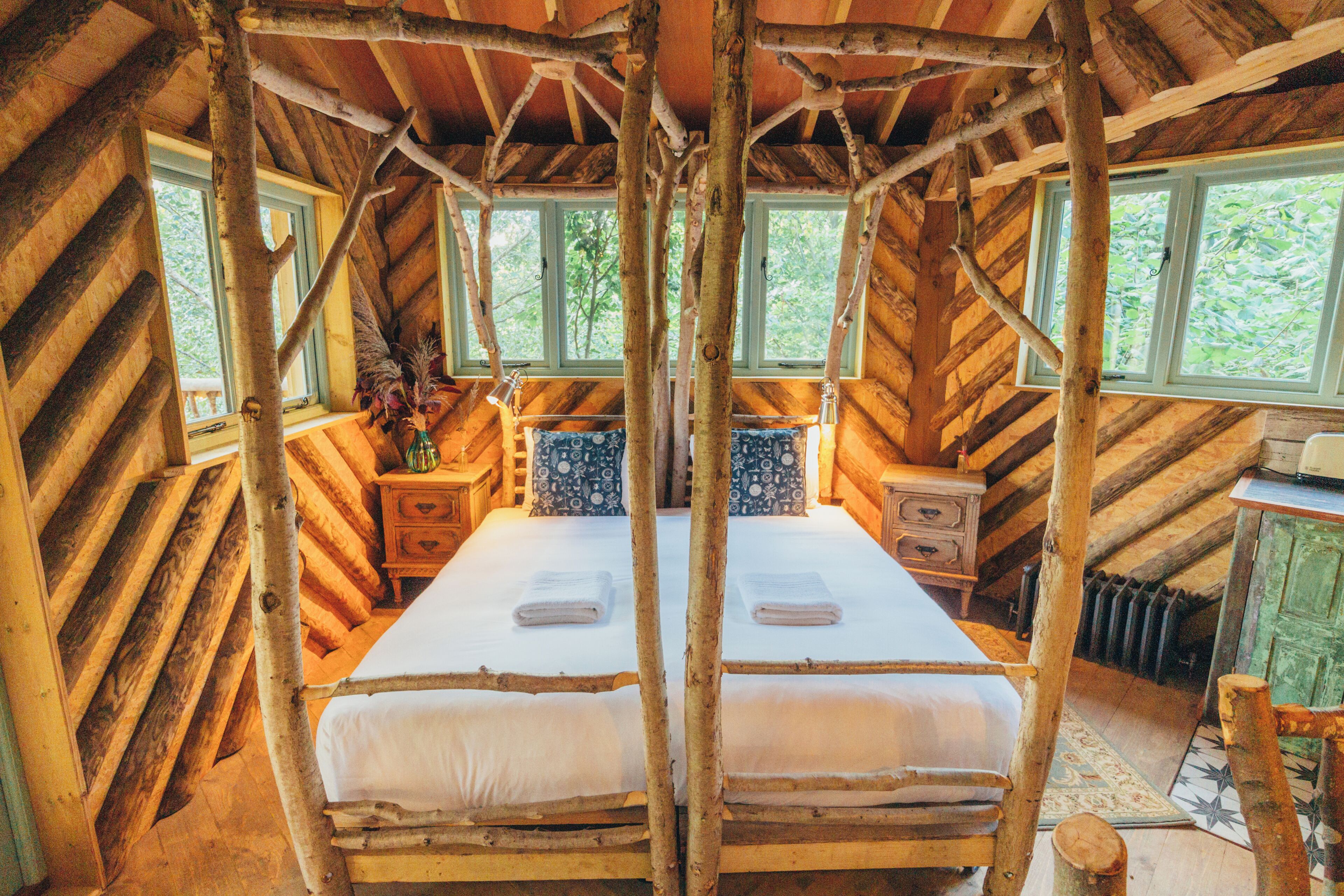 Une pièce rustique en bois, avec un lit, deux tables de chevet et une fenêtre.