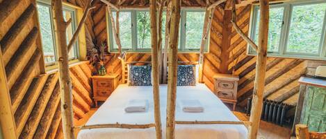 Une pièce rustique en bois, avec un lit, deux tables de chevet et une fenêtre.