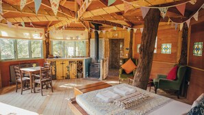 A rustic wooden cabin with a dining area, a kitchen, and a cozy living space with a bed. - West Lexham Wellness and Retreat Centre (King's Lynn)