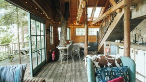A wooden cabin interior with a dining area, a staircase, and a view of the outdoors. - West Lexham Wellness and Retreat Centre (King's Lynn)