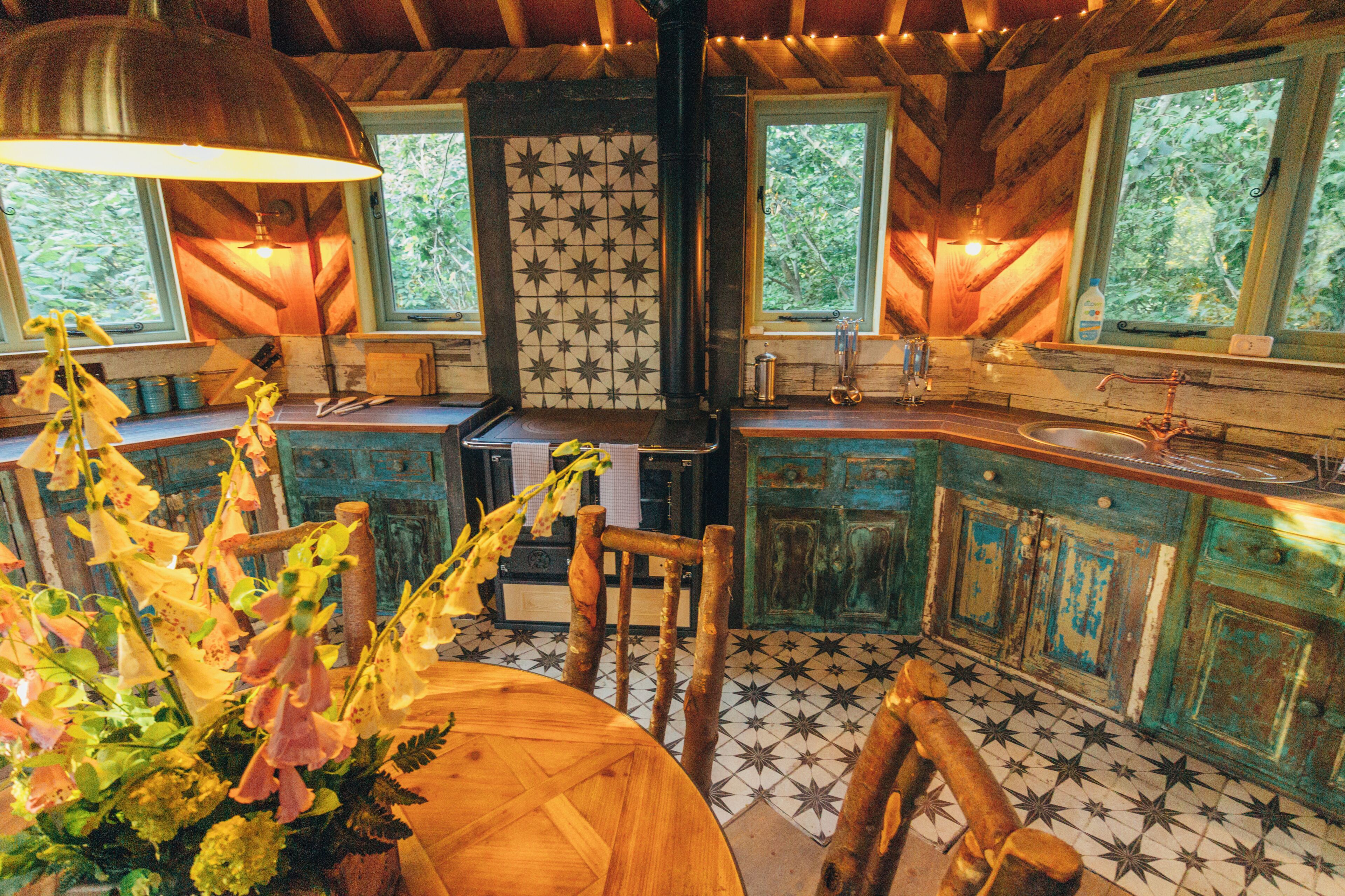 A rustic kitchen with a wooden table, chairs, and a tiled backsplash.