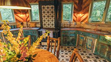 A rustic kitchen with a wooden table, chairs, and a tiled backsplash.