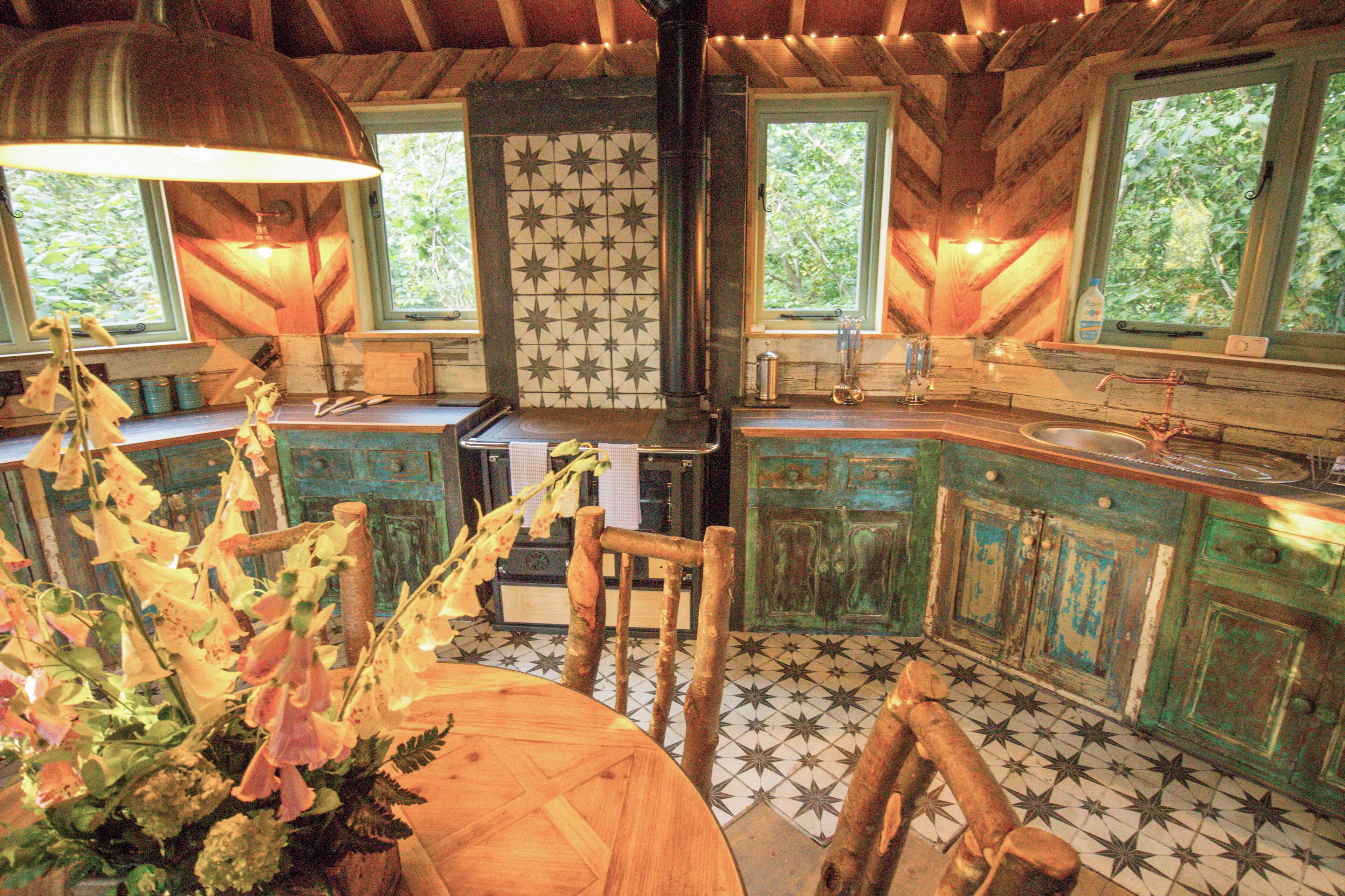 A rustic kitchen with wooden cabinets, a large window, and a tiled floor.