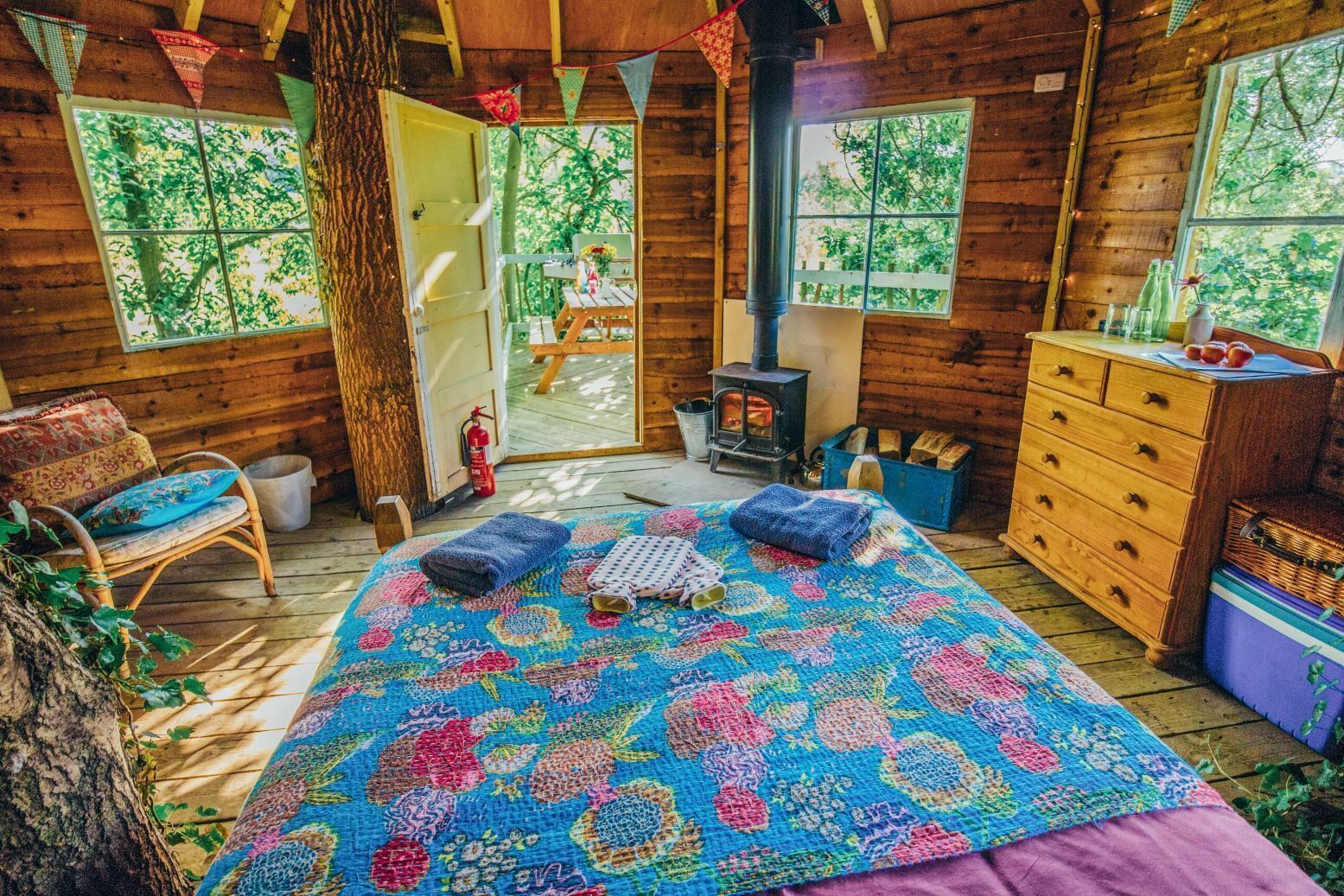 Ein gemütliches Blockhaus mit einem großen Bett, einem Schminktisch, einem Holzstuhl und einem Kamin.