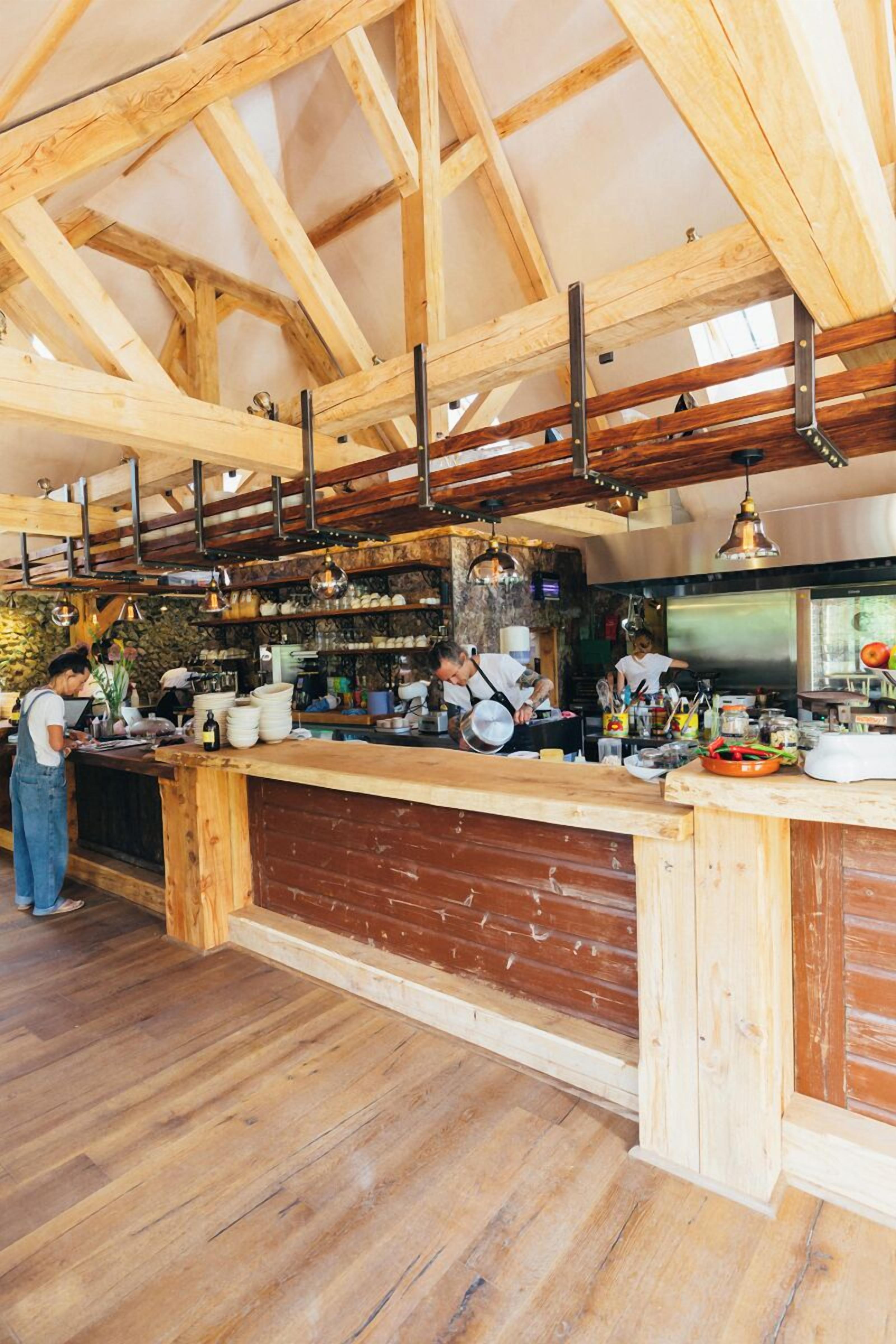 A rustic kitchen with exposed wooden beams, a wooden counter, and a stone wall.