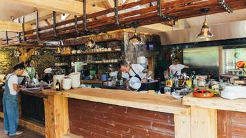 A rustic kitchen with exposed wooden beams, a wooden counter, and a stone wall.