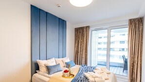 A modern hotel room with a large bed, a view of the city through the window, and a balcony. - Apartment in Rogowo Near Beach and Lake (Trzebiatow)